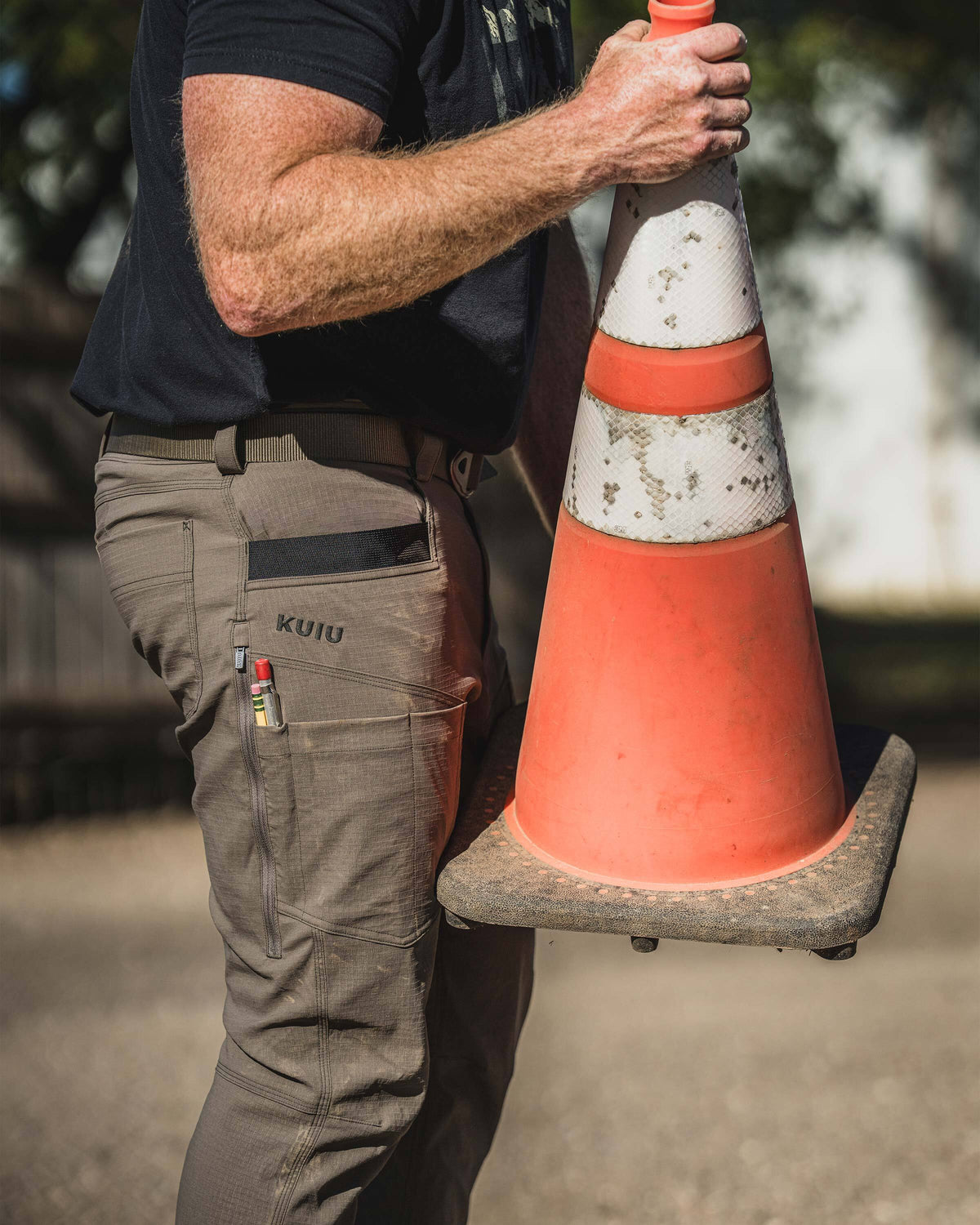 Man holding a traffic cone at a worksite, wearing Motive Workgrade Pant in Rodeo Brown
